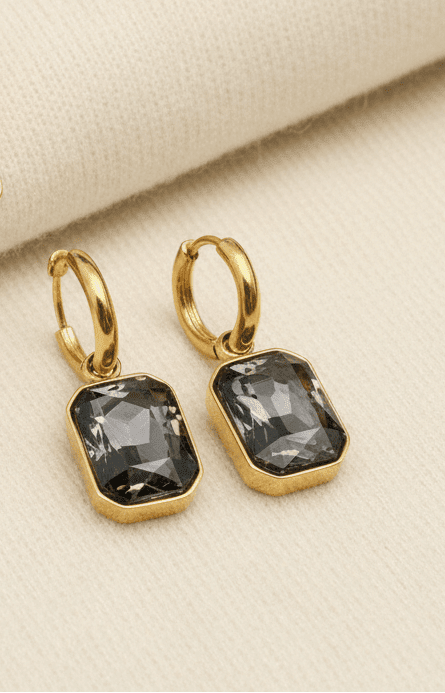 Mixing Metals Jewelry including a pair of gold and smoky quartz huggie earrings on an ivory sweater fabric background
