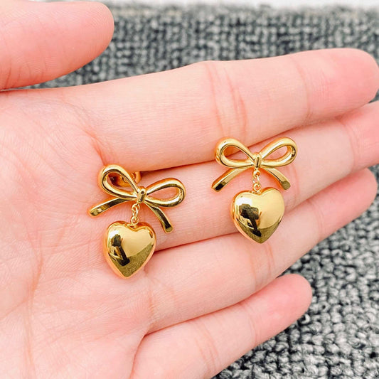 Gold Bow earrings on a person's hand
