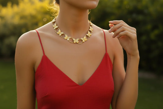 A woman wearing a red dress and gold butterfly link necklace in a outdoor setting