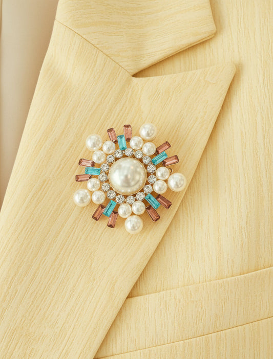 a pearl and crystal encrusted snowflake shaped brooch on the lapel of a yellow colored blazer