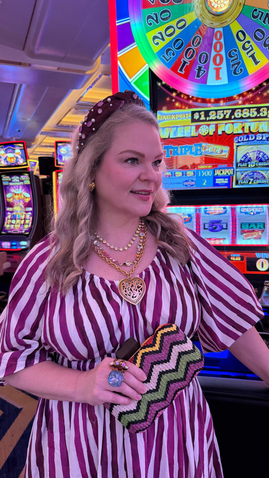 woman in striped dress with layered necklaces in a casino setting