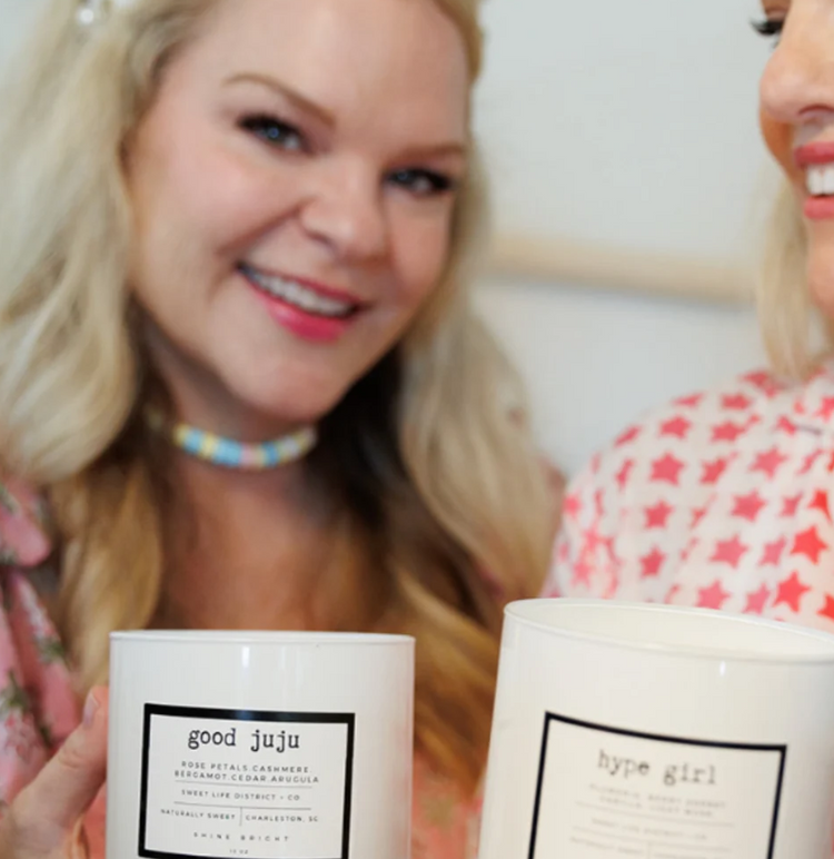 Two women holding candles in their hands in a an indoor setting