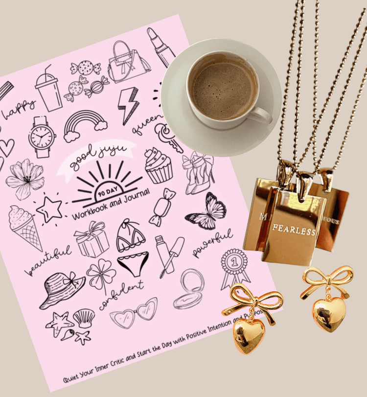Good JuJu 90 Day workbook with coffee cup, "fearless" engraved necklace, and gold bow earrings in a flay lay