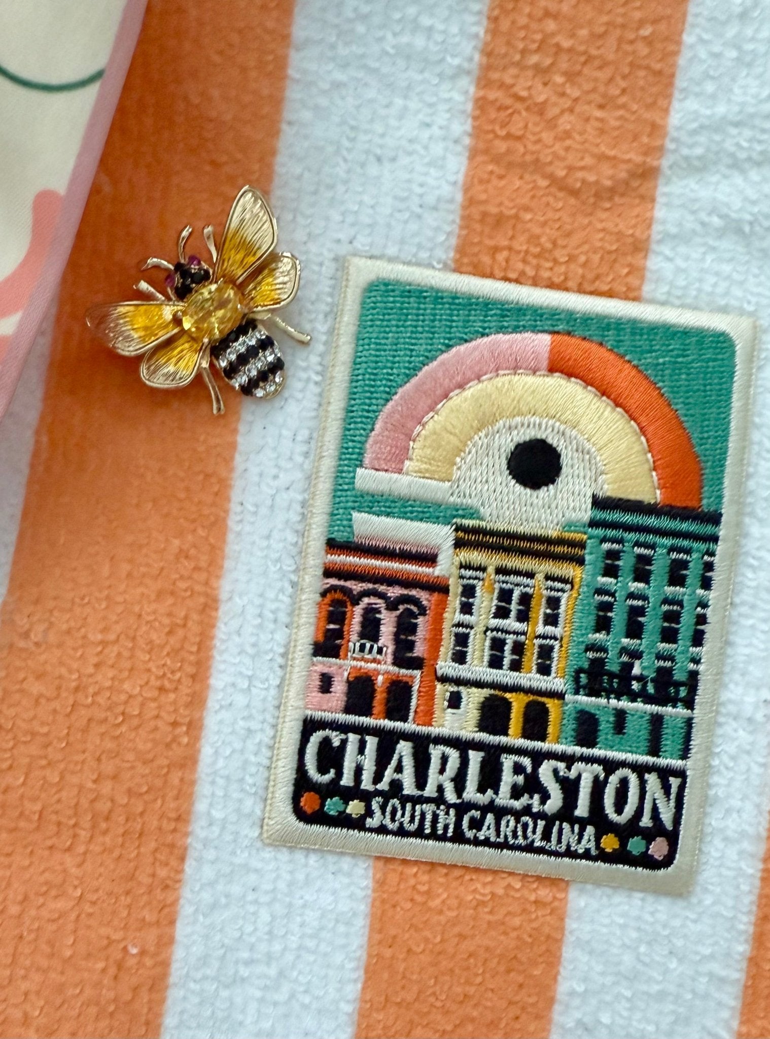 Embroidered patch of Charleston, South Carolina, with a bee pin on a striped terrycloth bag