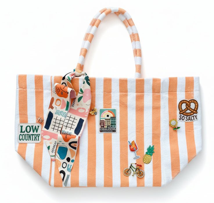 Coral striped terrycloth tote bag with decorative patches, pins and a scarf on a white background