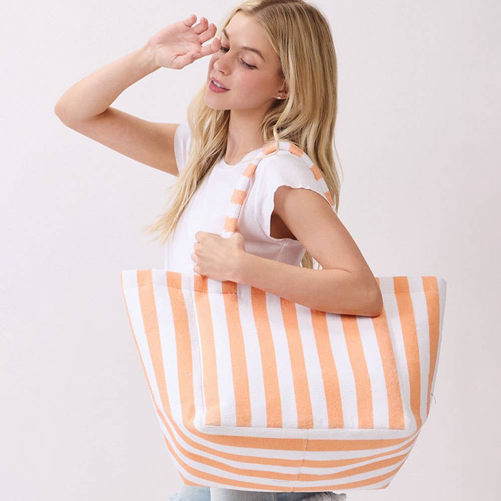 Woman holding a large orange and white striped terrycloth tote bag against a plain background