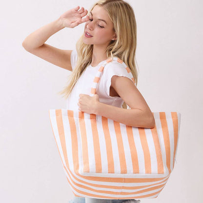 Woman holding a large orange and white striped terrycloth tote bag against a plain background