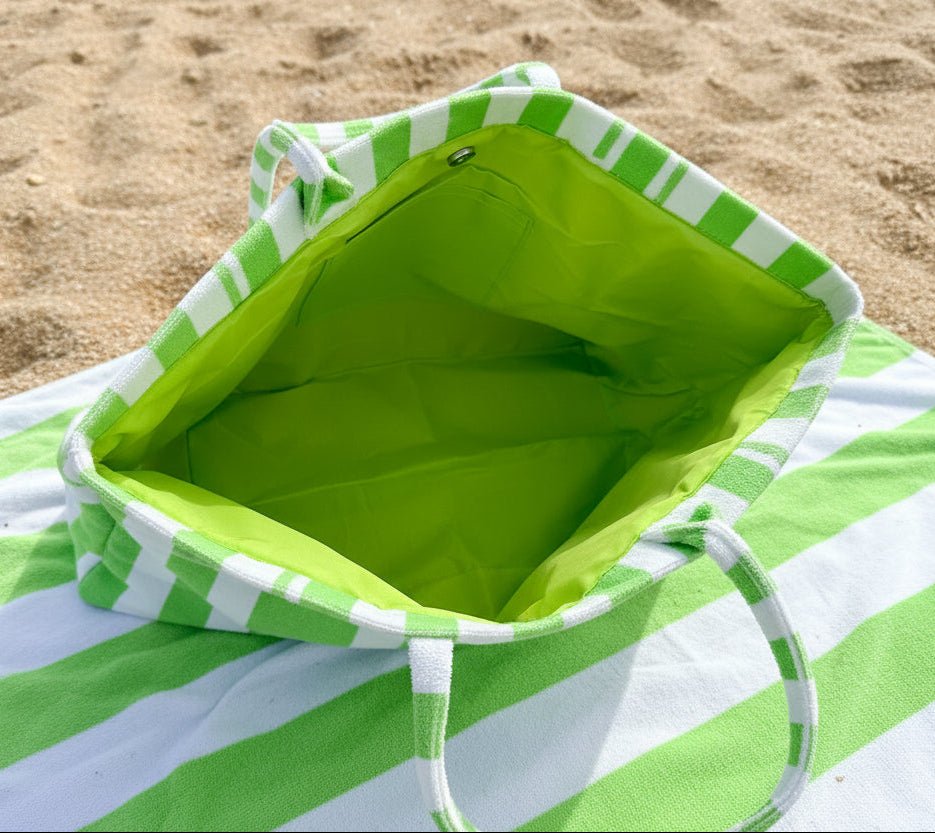 Green and white striped bag with a hand holding it from the top to show inside of tote with magnetic closure and inner slip pocket.