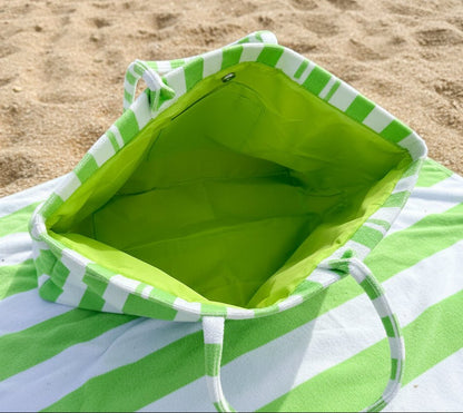 Green and white striped bag with a hand holding it from the top to show inside of tote with magnetic closure and inner slip pocket.