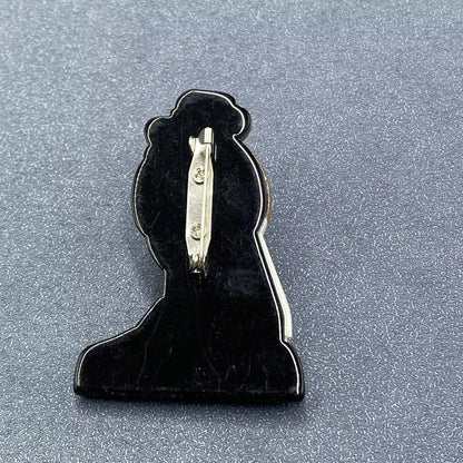 back view of fashionista brooch showing pin closure against a textured grey background