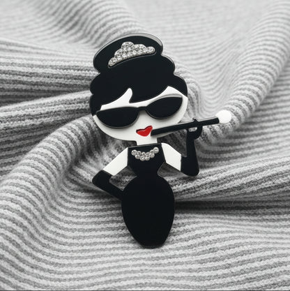 Audrey fashionista acrylic brooch pin on grey and white striped fabric. 
