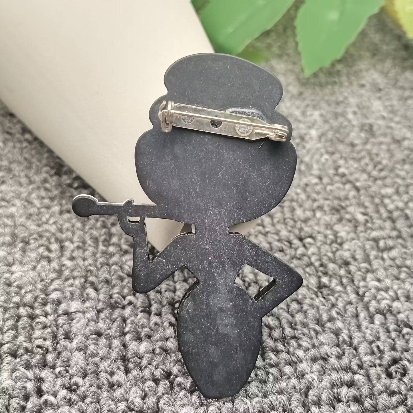 Back view of Audrey fashionista brooch to show pin closure against a grey carpet background leaning against a white vase