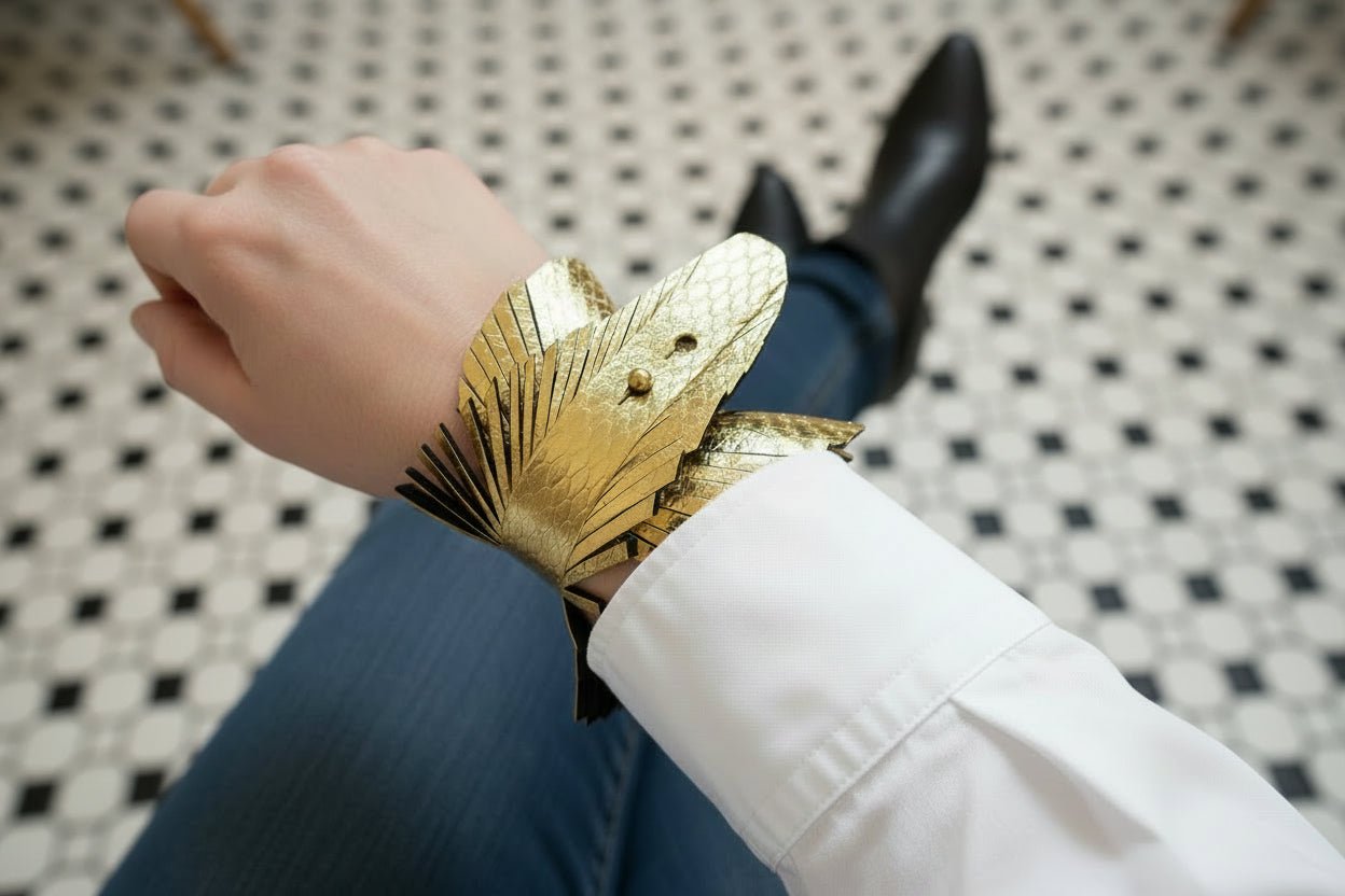 person wearing a gold snakeskin embossed cuff bracelet with jeans and black boots in a cafe setting