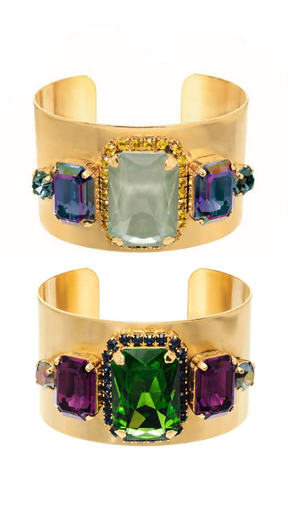 Two gold cuff bracelets with multicolored gemstones on a white background