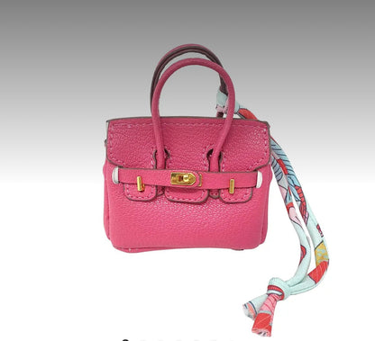 Pink handbag bag charm with a colorful strap on a gray background