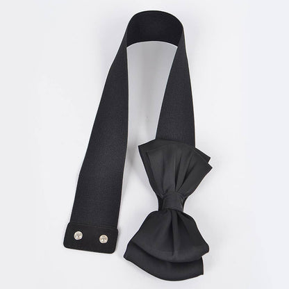 Flat lay of a black bow stretch belt showing the snap closure on a white surface