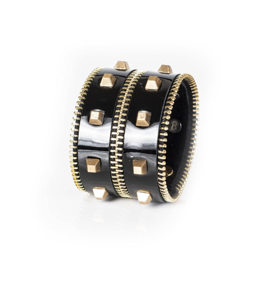 Black leather studded cuff bracelet with gold studs and zipper detail against a white background