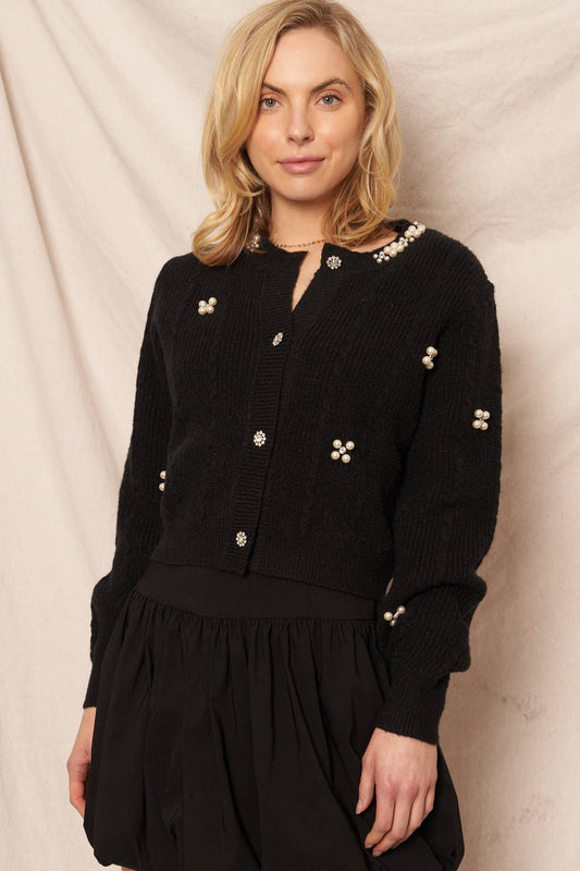 Woman wearing a black outfit with decorative buttons against a beige background