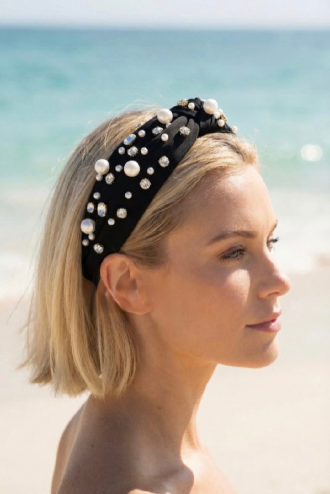 Woman wearing a black pearl and crystal embellished headband on a beach