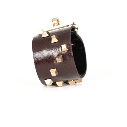 brown leather cuff with gold hardware against a white background