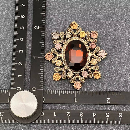 Cognac crystal starburst brooch next to a ruler for scale against a grey textured background