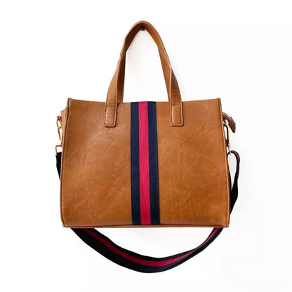 Cognac vegan leather messenger tote with navy and red stripe detail — front view showing structured silhouette and gold hardware