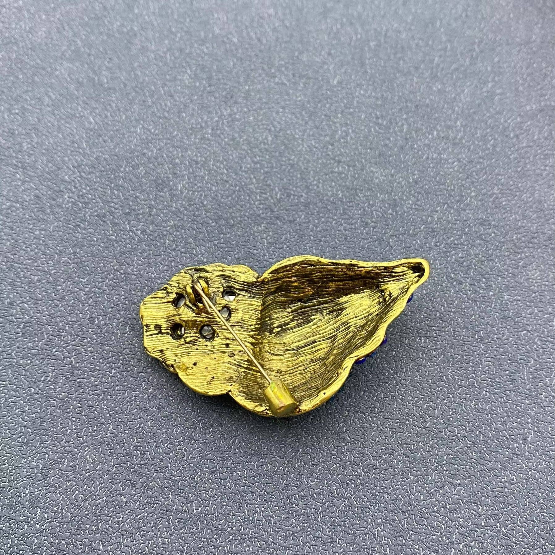 back view of conch shell brooch showing pin closure against a grey background