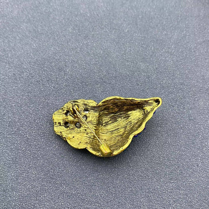 back view of conch shell brooch showing pin closure against a grey background