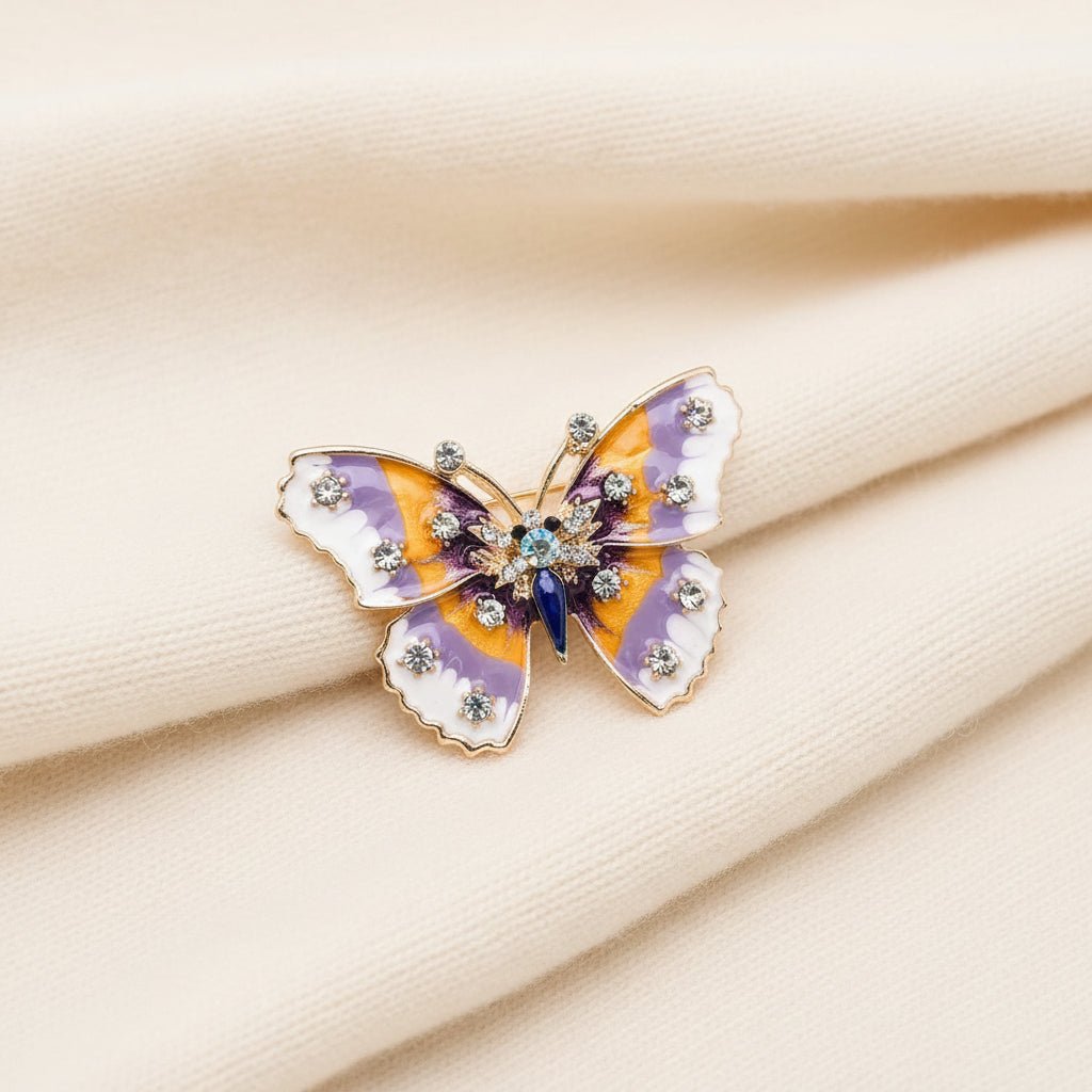 Butterfly-shaped brooch with purple and orange wings on an ivory fabric background