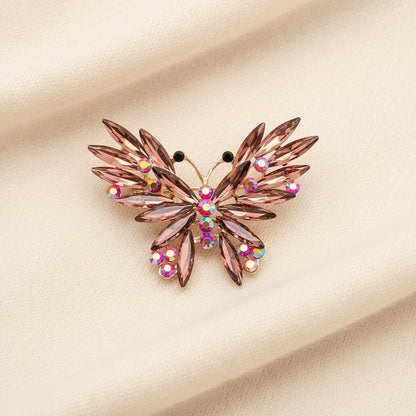 Decorative butterfly brooch with gemstones laying on an ivory sweater fabric
