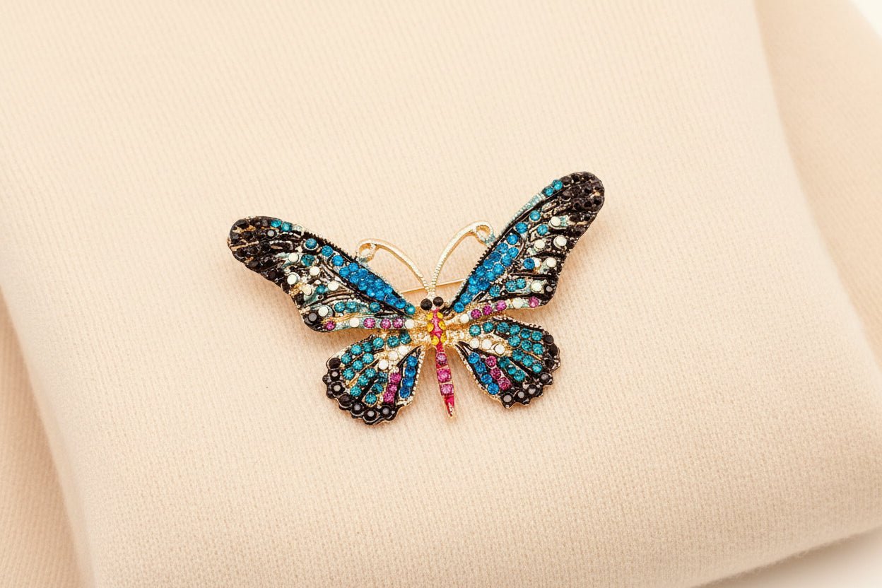 Butterfly-shaped brooch with colorful gemstones laying on an ivory sweater 