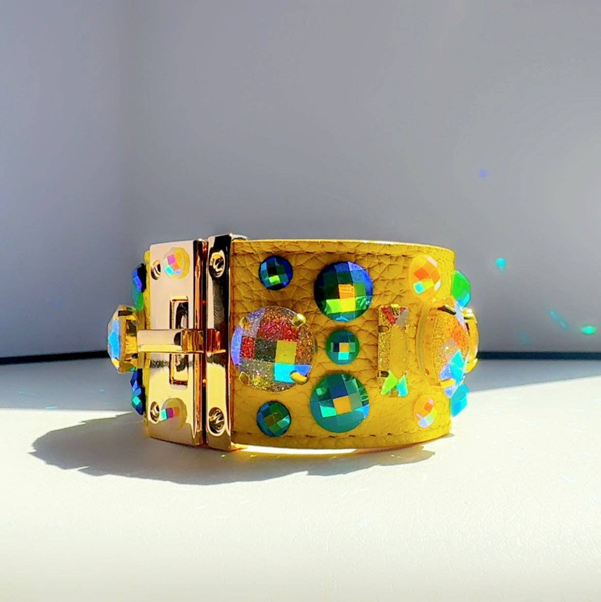 yellow leather bracelet with colorful gemstones on a light gray background