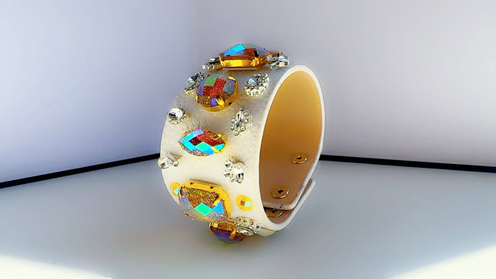 Decorative white leather bracelet with colorful gemstones on a white background