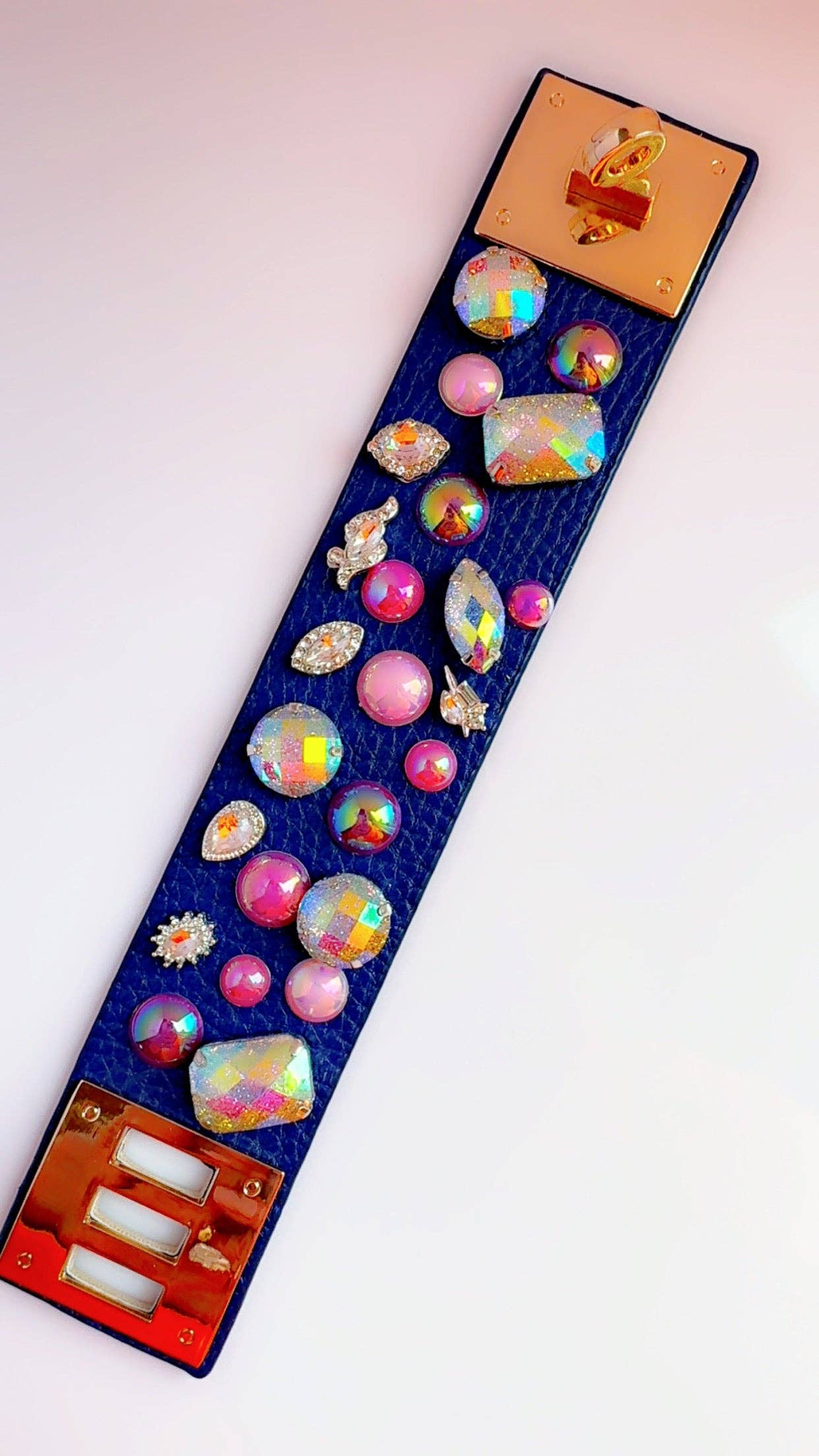 bird's eye view of a navy leather cuff bracelet with decorative beads laying on a white surface