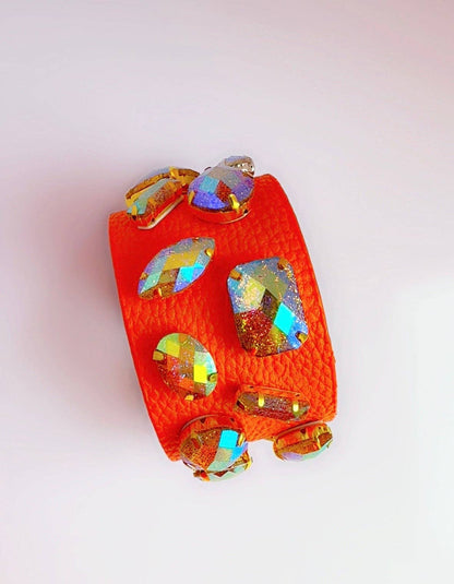 Orange leather cuff bracelet with colorful gemstones on a white surface