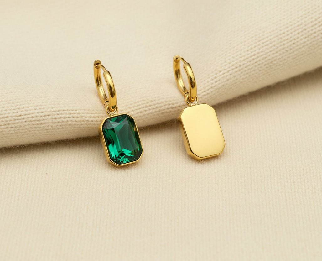 Gold and green gemstone earrings with green gemstone on an ivory sweater material background. one earring is the front view and one earring is the back view.