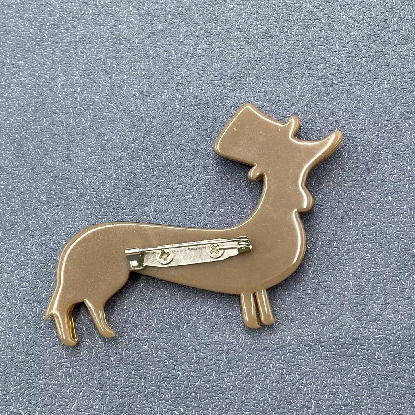 Back view of a dog-shaped brooch on a gray background