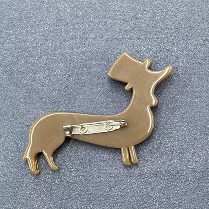 Back view of a dog-shaped brooch on a gray background