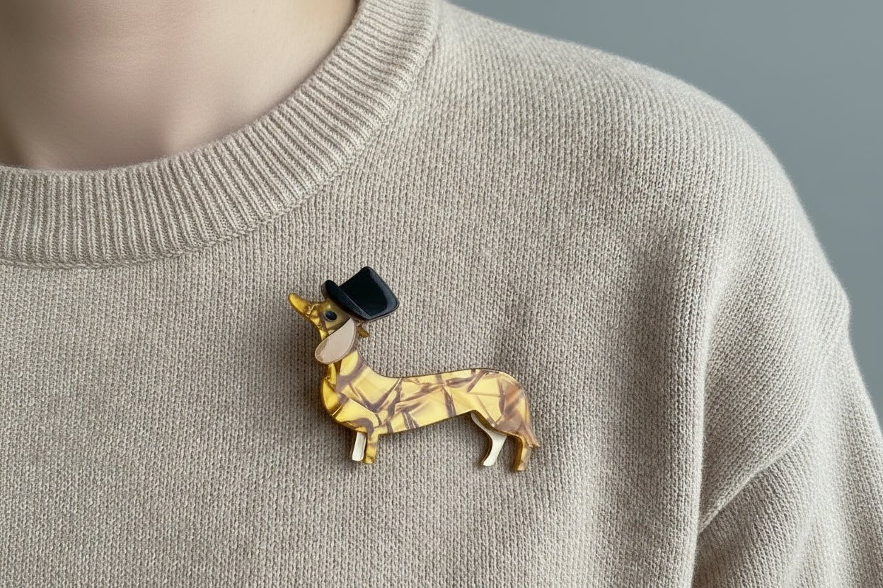 Gold dachshund dog figurine with a black top hat on a light tan sweater