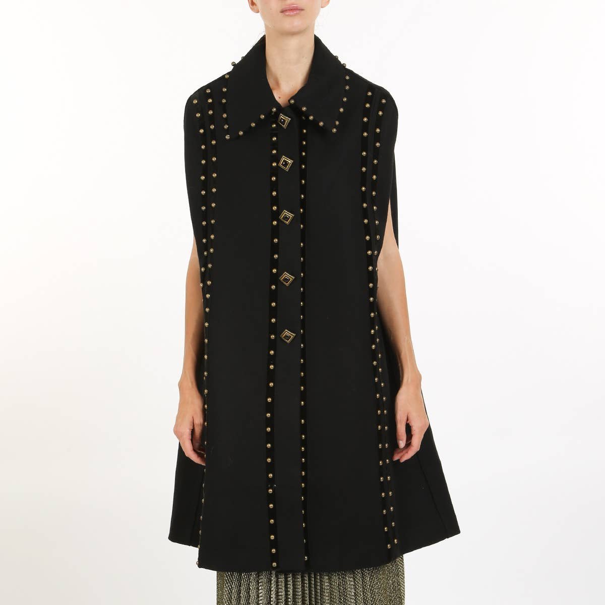 a woman wearing a black cape coat with gold stud details against a white background