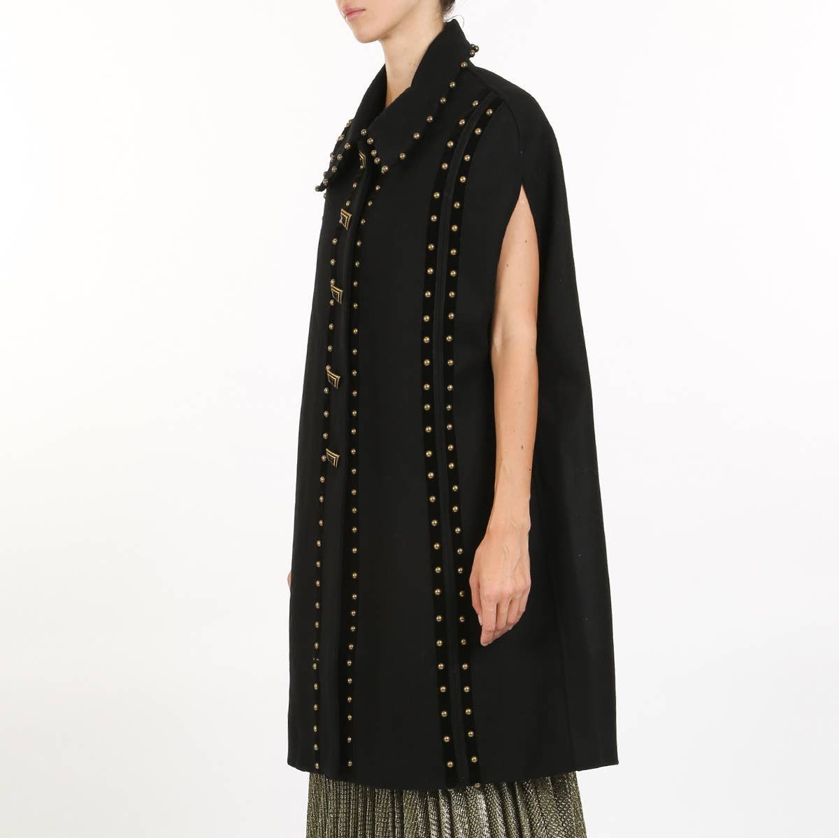 side angled view of a woman wearing a black cape coat with gold stud detailing against a white background