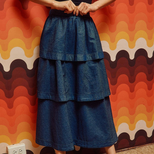 woman wearing denim tiered midi skirt in front of geometric wall