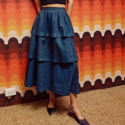 woman in black heels wearing denim tiered midi skirt in front of geometric wall
