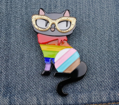 Color cat shaped brooch with gold glasses on a denim fabric background