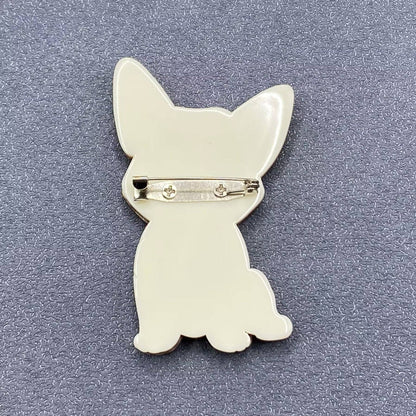 The back view of a Corgi dog brooch to show the pin closure against a grey textured background