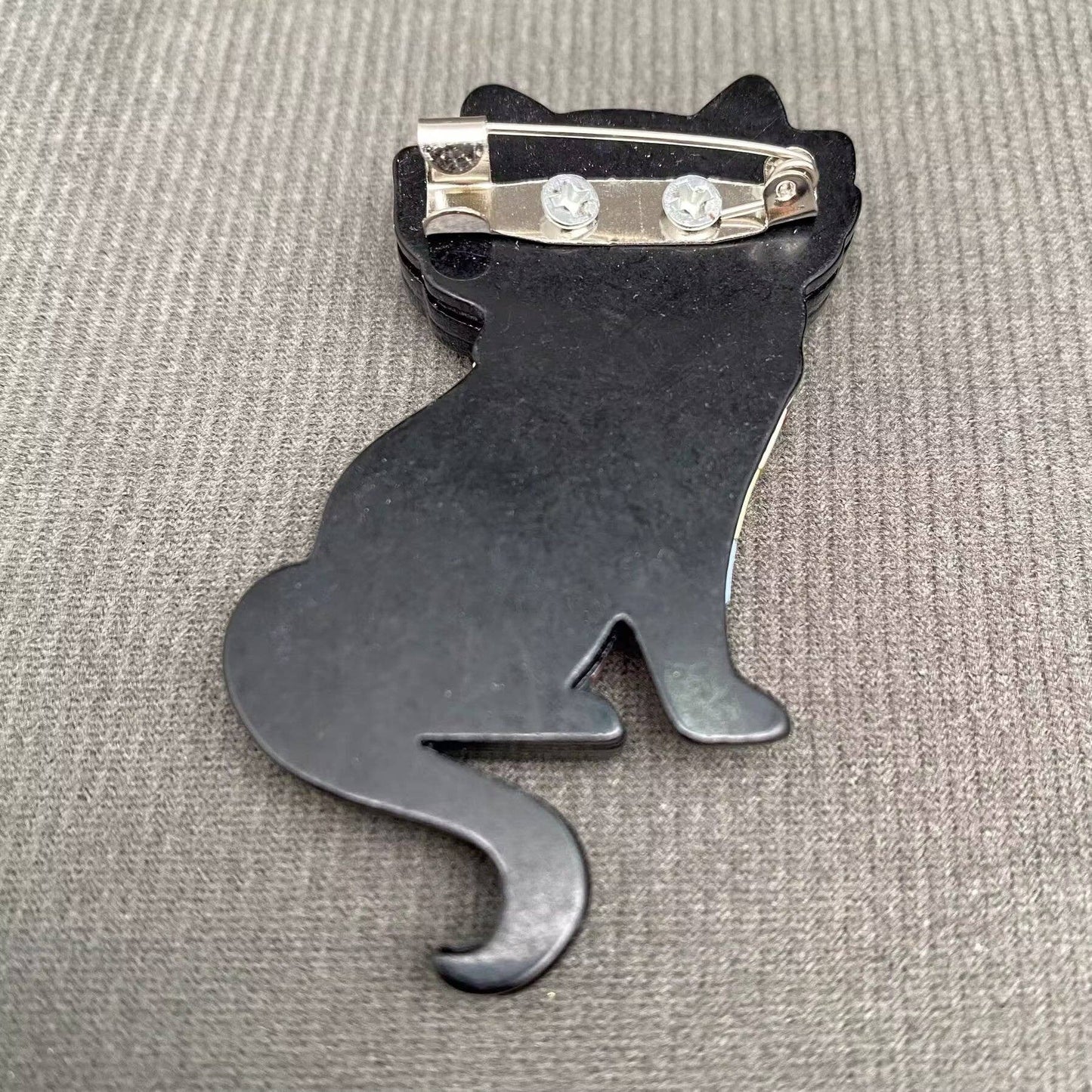 Back view of a cat brooch to show the pin closure against a grey background