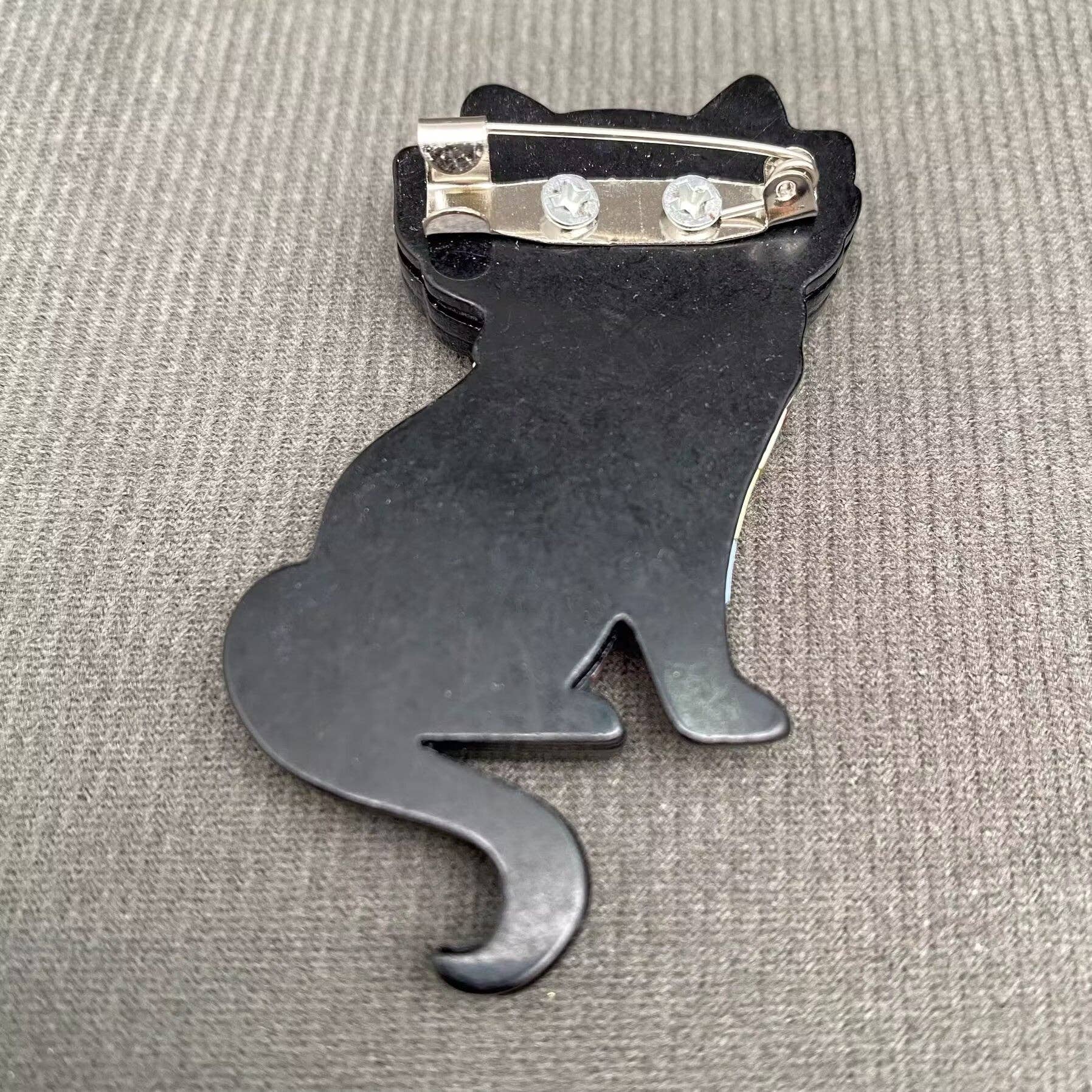 Back view of a cat brooch to show the pin closure against a grey background