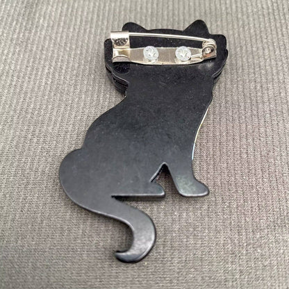 Back view of a cat brooch to show the pin closure against a grey background