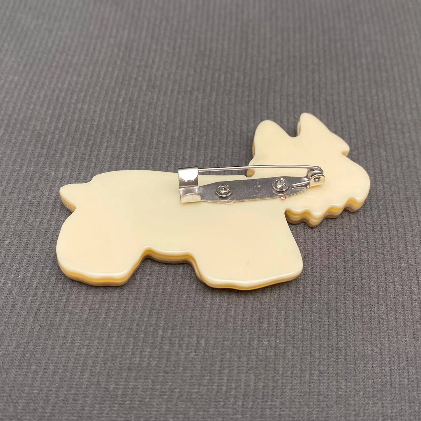 Back view of a white Yorki dog showing the pin closure against a grey background