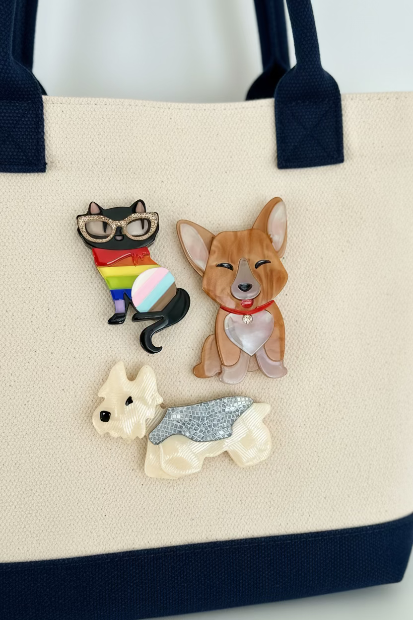 Three acrylic brooches on a canvas bag with navy blue trim including a cat, corgi, and yorki